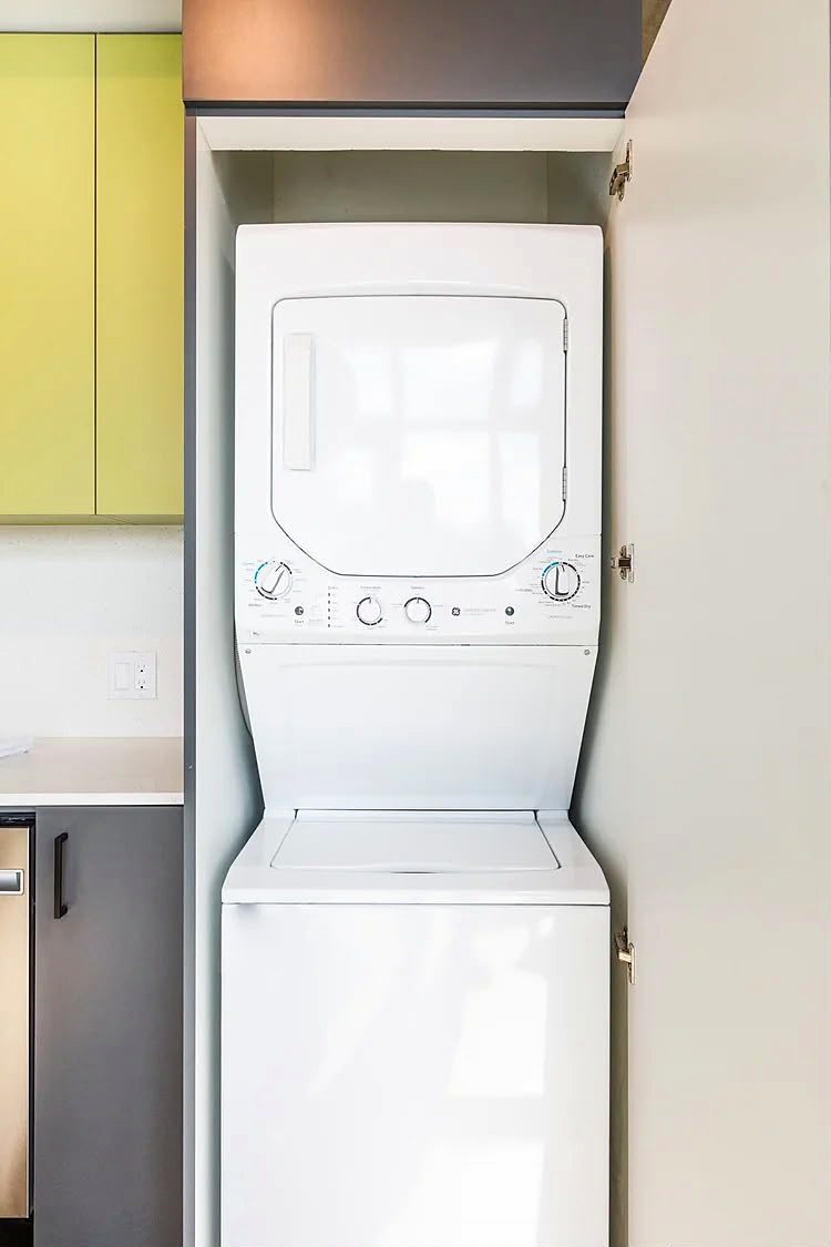 Full-size stacked washer and dryer inside a purpose-built cabinet with the door open.