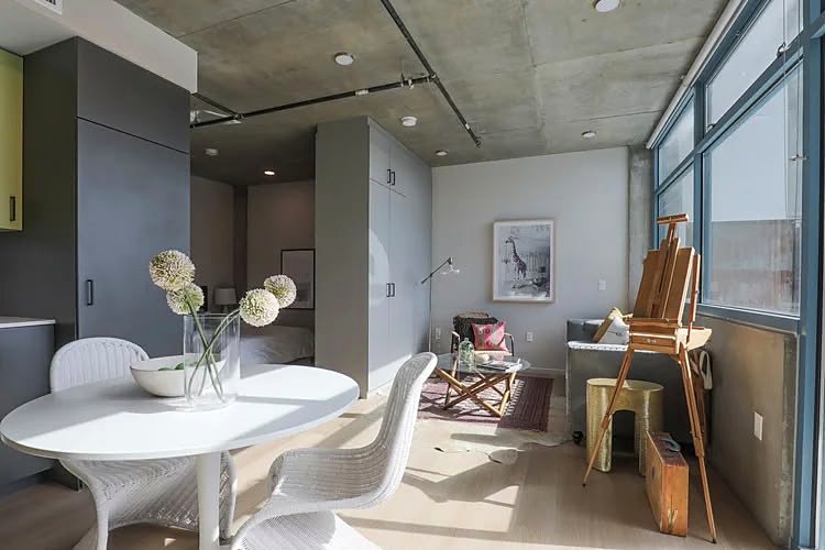 Compact studio kitchen with full-size appliances, and a sleeping alcove screened off behind it.